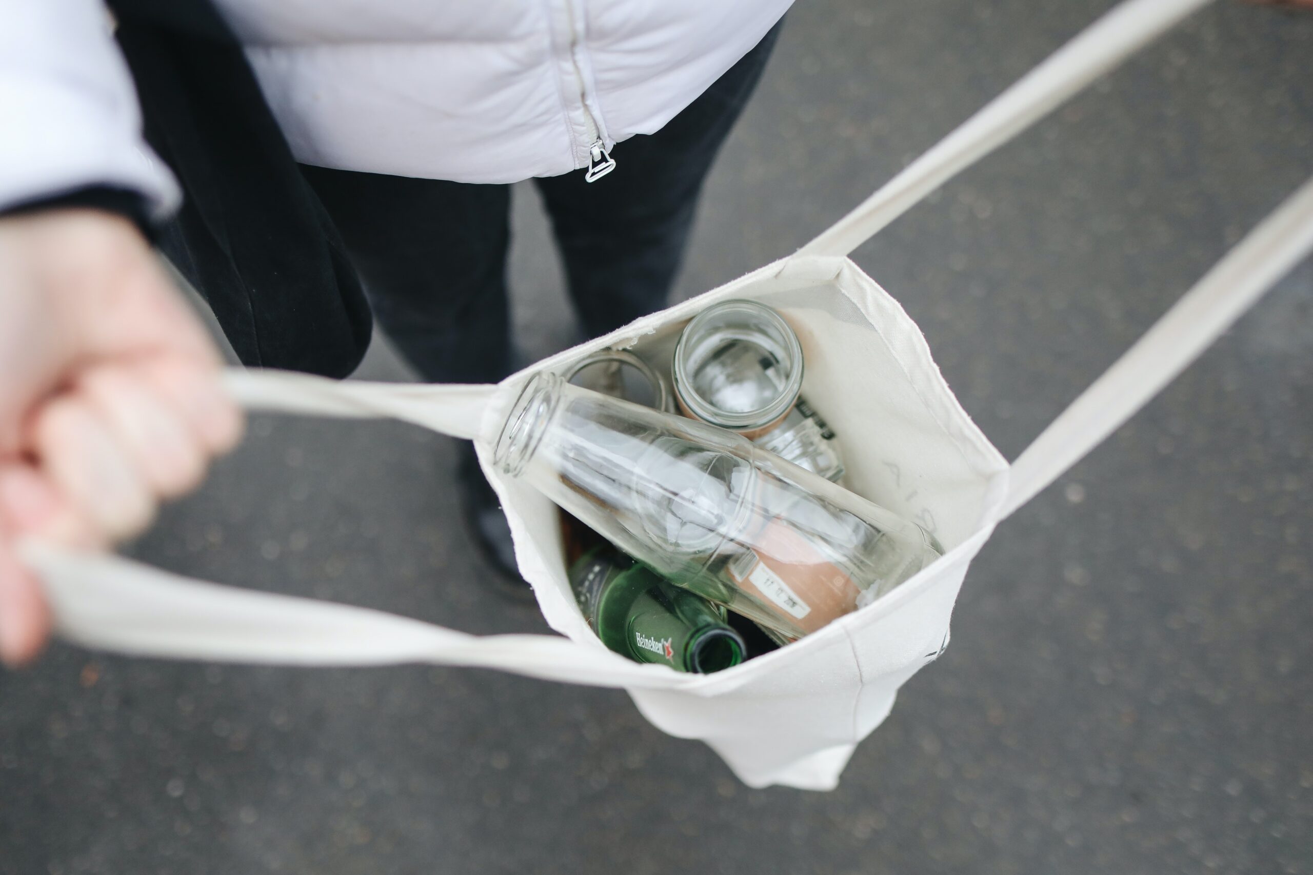 person holding bag of recyclable glass bottles