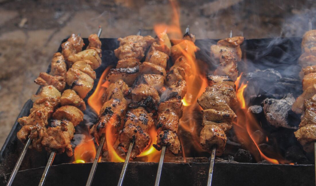 grilled meat on skewers over charcoal grill flames apartments in north austin