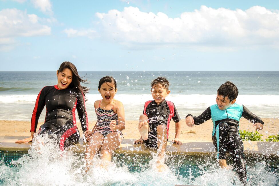 woman and three kids splashing in water on beach Luxury Apartment in Midtown Houston